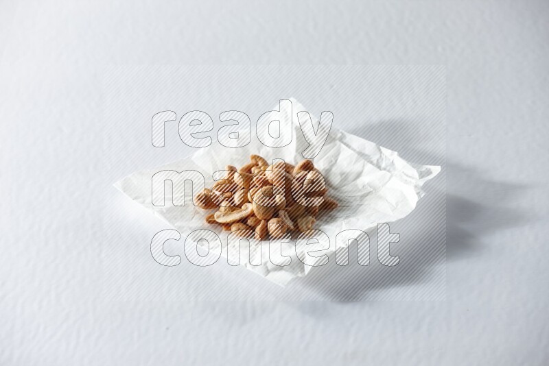 Cashews on a crumpled piece of paper on a white background in different angles