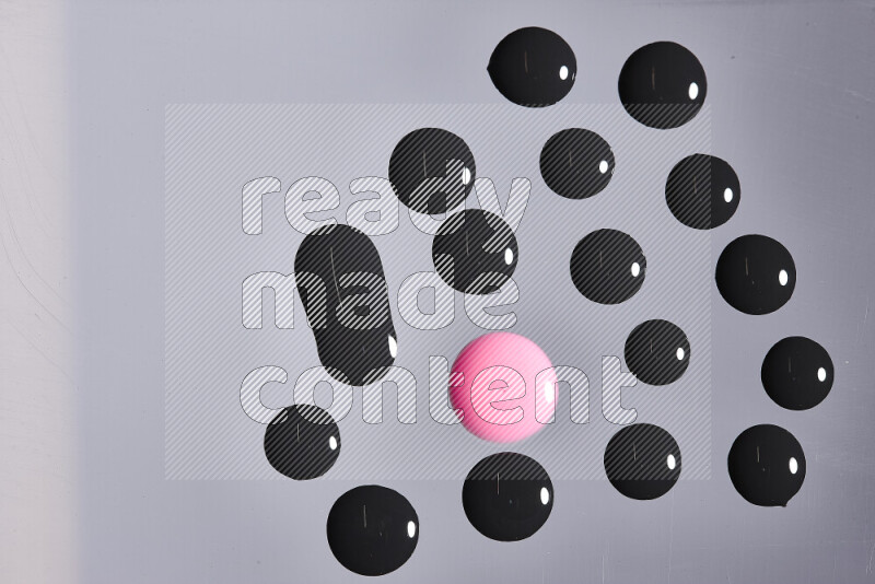 Close-ups of abstract pink and black paint droplets on the surface