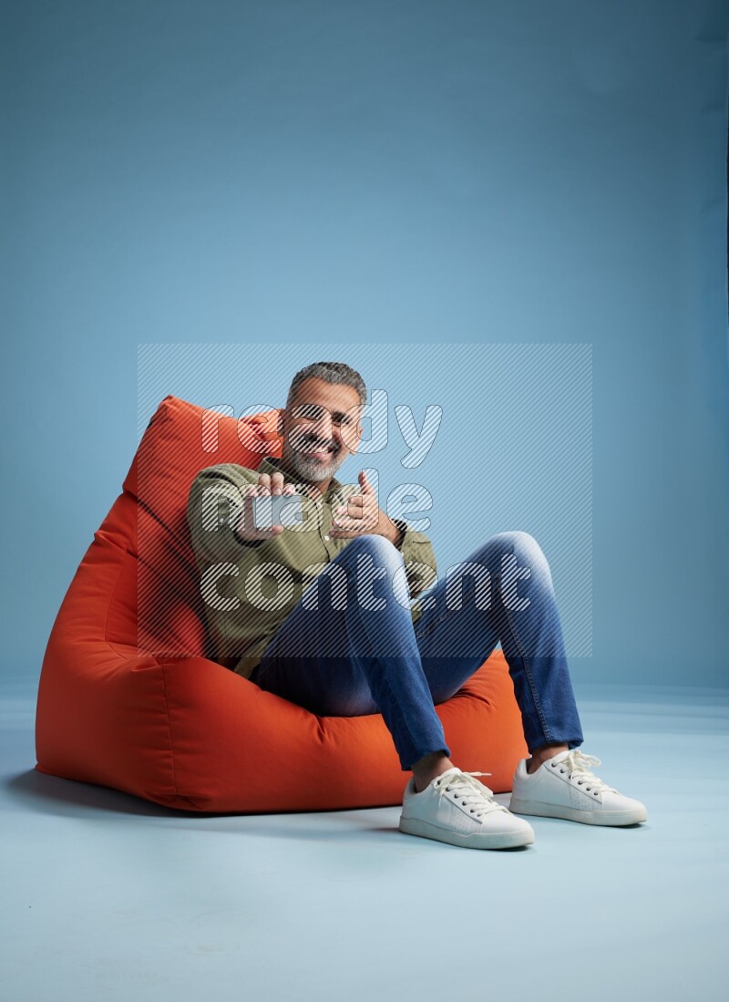 A man sitting on an orange beanbag and holding ATM card