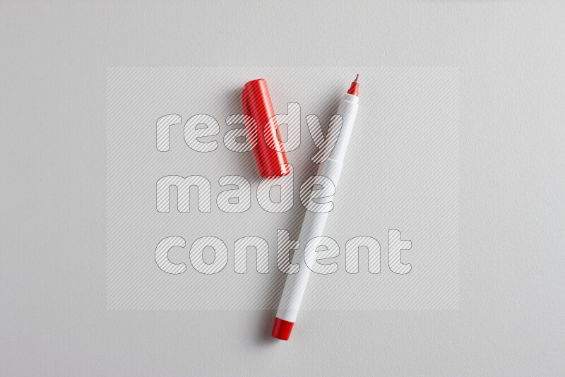 A close-up showing an open single coloring pen with a cap on grey background