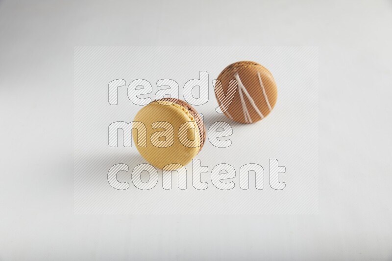 45º Shot of of two assorted Brown Irish Cream, and Yellow, and Brown Chai Latte macarons on white background