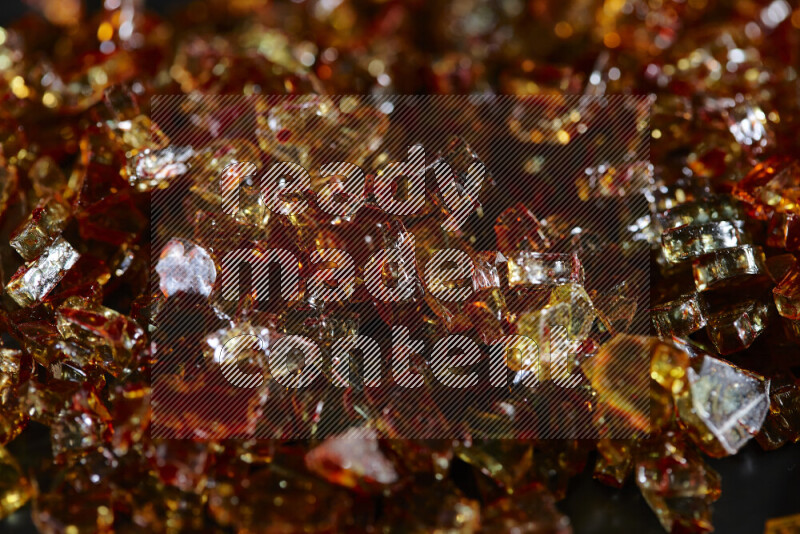 Transparent orange fragments of glass scattered on a black background