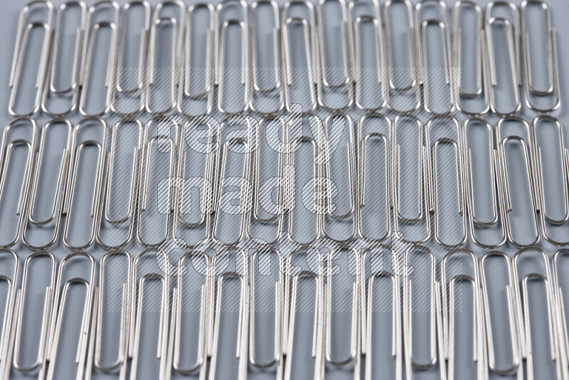 Silver paper clips isolated on a grey background
