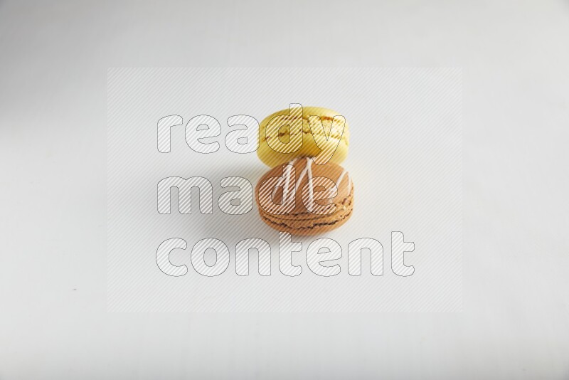 45º Shot of of two assorted Brown Irish Cream, and Yellow Lemon macarons on white background