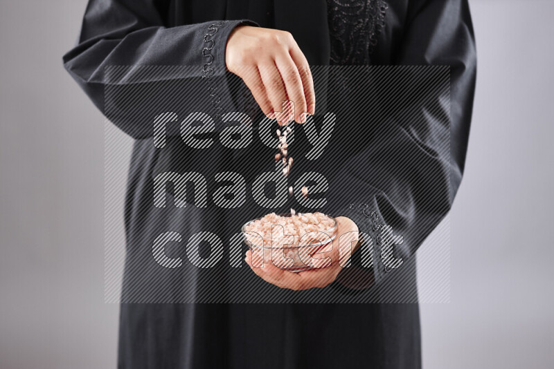 Woman in abaya holding different kinds of spices in different positions