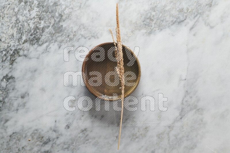 Wheat stalks on multicolored pottery oven plate on grey marble background