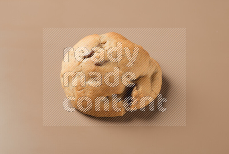 a whole chocolate chip cookie on a brown background