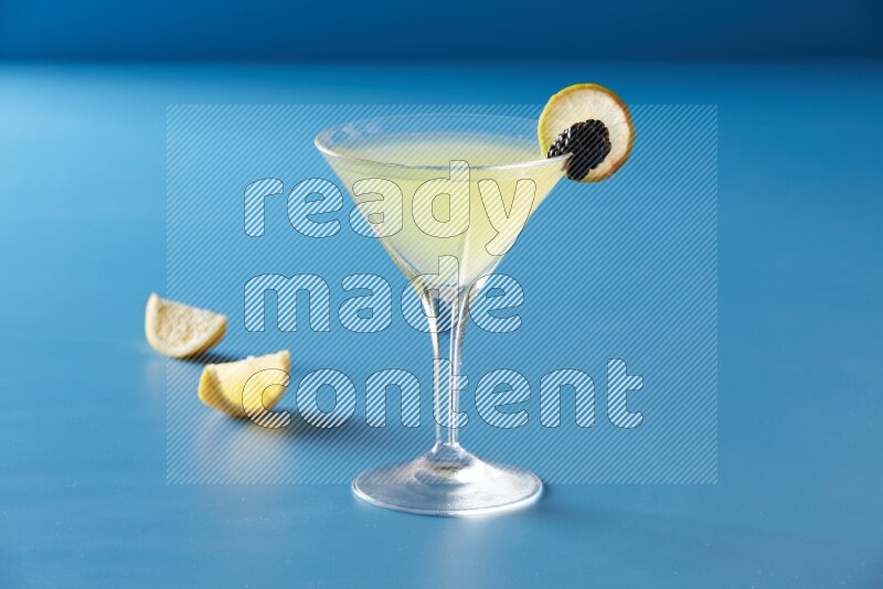 glass of lemon juice with lemon slice and berry on blue background