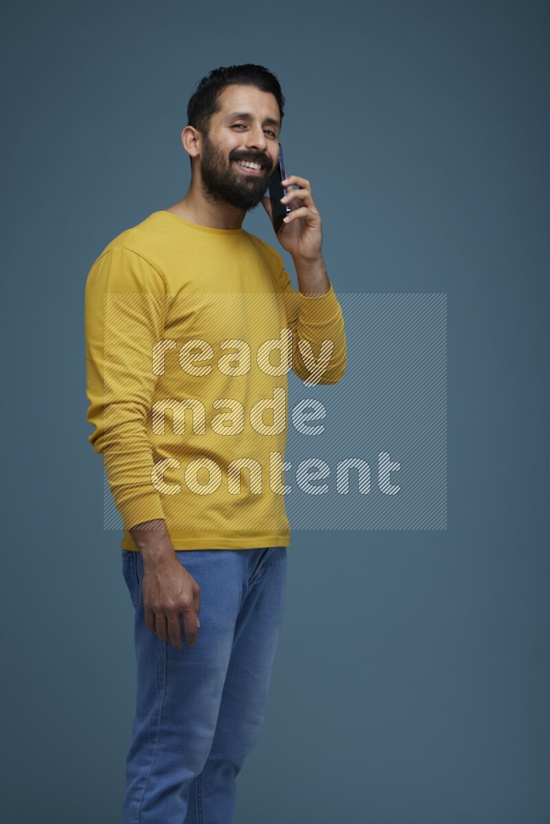 A man having a calling in a blue background wearing a yellow shirt