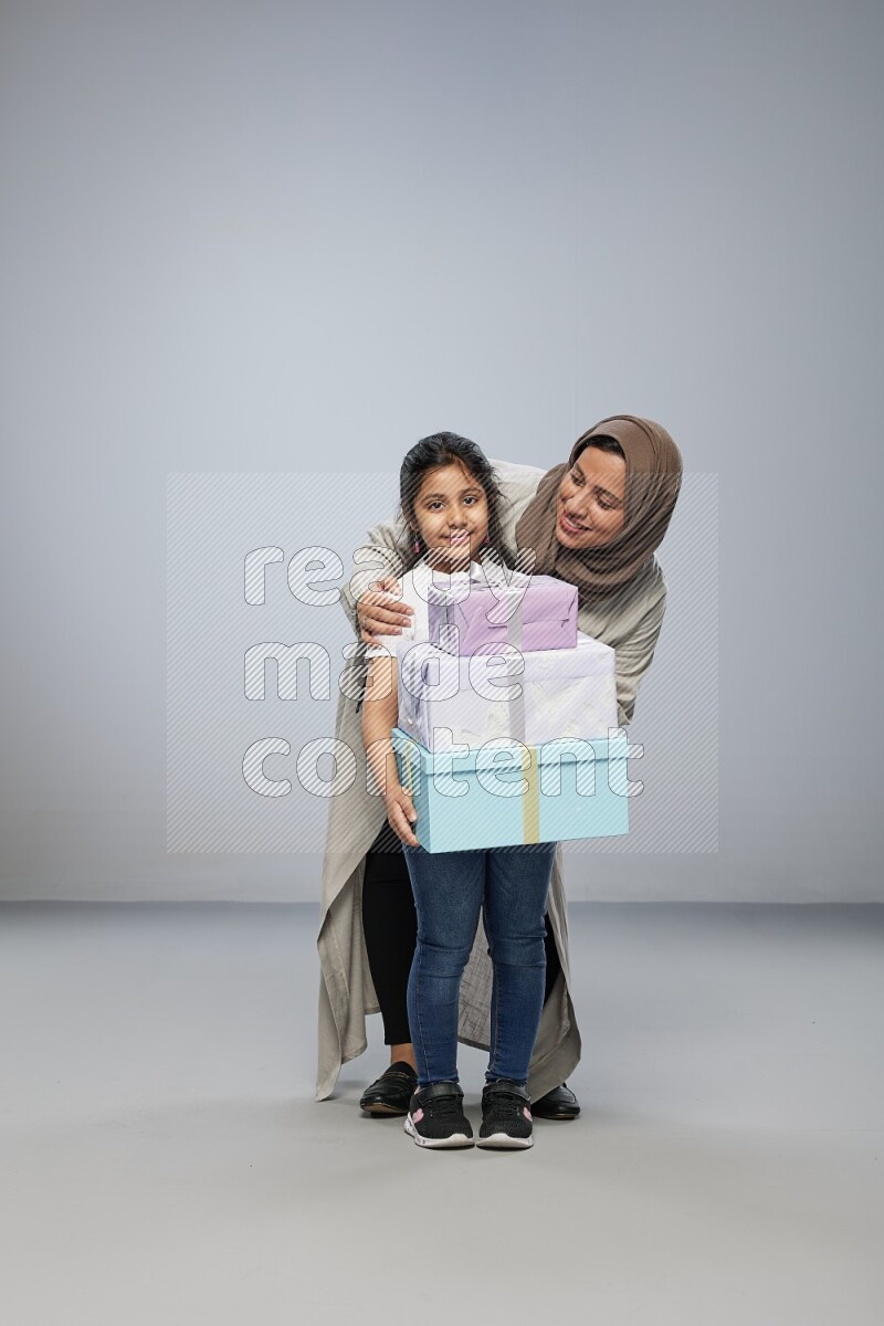 A girl giving a gift to her mother on gray background