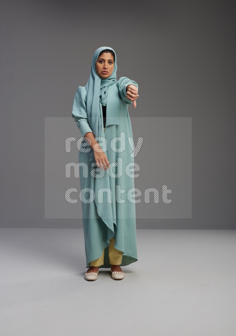 Saudi Woman wearing Abaya standing interacting with the camera on Gray background