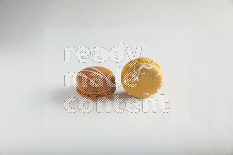 45º Shot of of two assorted Brown Irish Cream, and Yellow Piña Colada macarons on white background