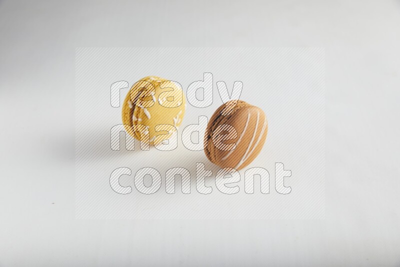 45º Shot of of two assorted Brown Irish Cream, and Yellow Piña Colada macarons on white background