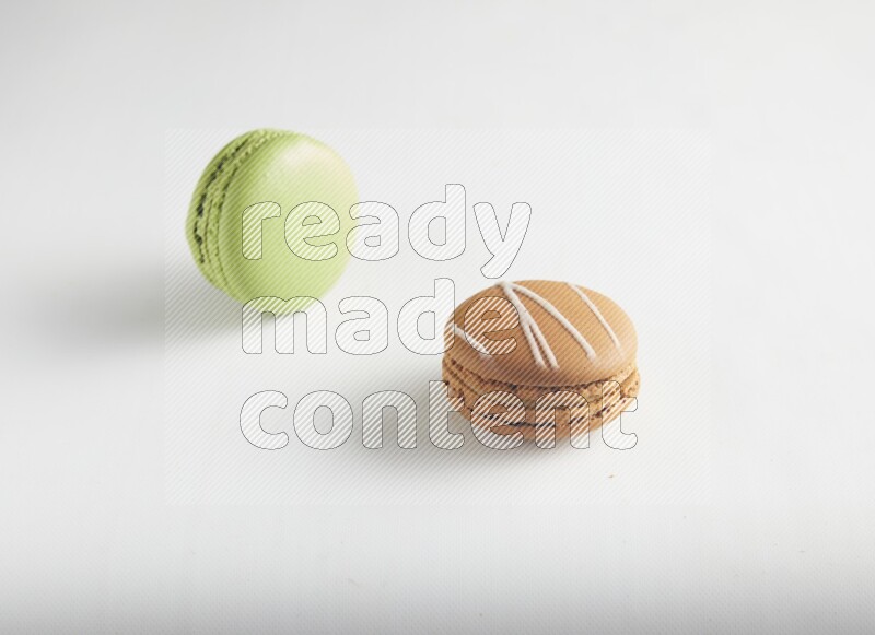 45º Shot of of two assorted Brown Irish Cream, and Green Pistachio macarons on white background