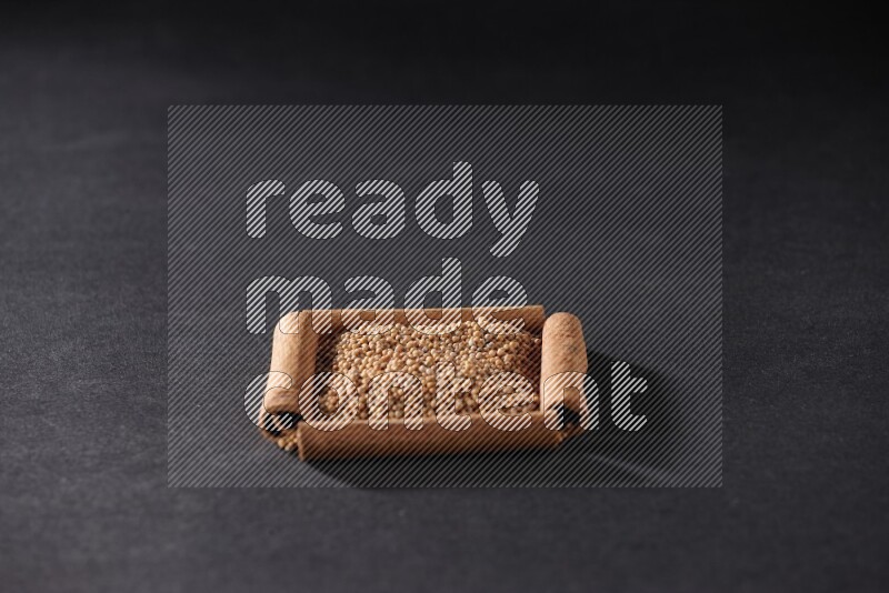 A single square of cinnamon sticks full of mustard seeds on black flooring