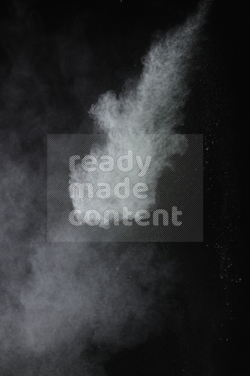 A side view of green powder explosion on black background