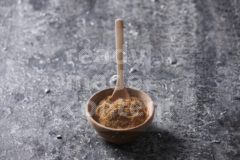 Wooden bowl full of cinnamon powder with a wooden spoon on a textured black background in different angles