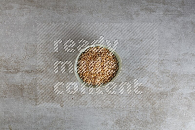 corn kernel in a green ceramic bowl on a grey textured countertop