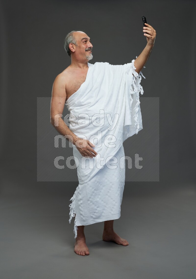A man wearing Ehram Standing taking selfie on gray background