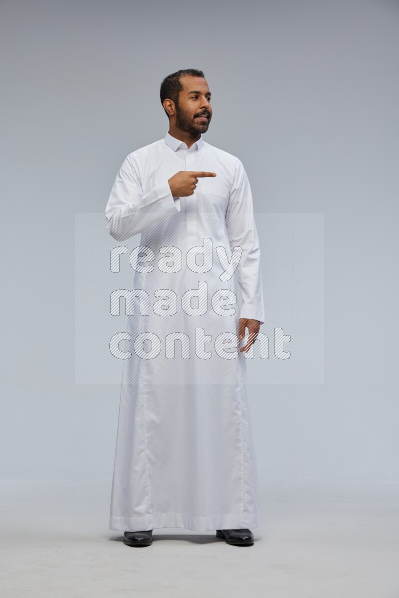 Saudi man Wearing Thob standing interacting with the camera on Gray background
