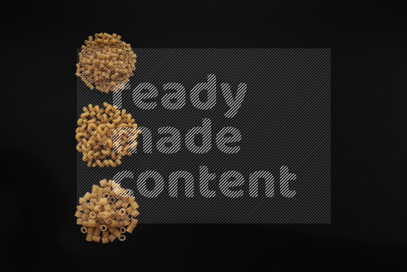 Different pasta types in 3 bunches on black background