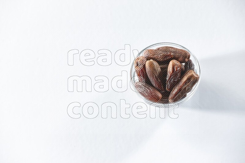 A glass bowl full of dried dates on a white background in different angles
