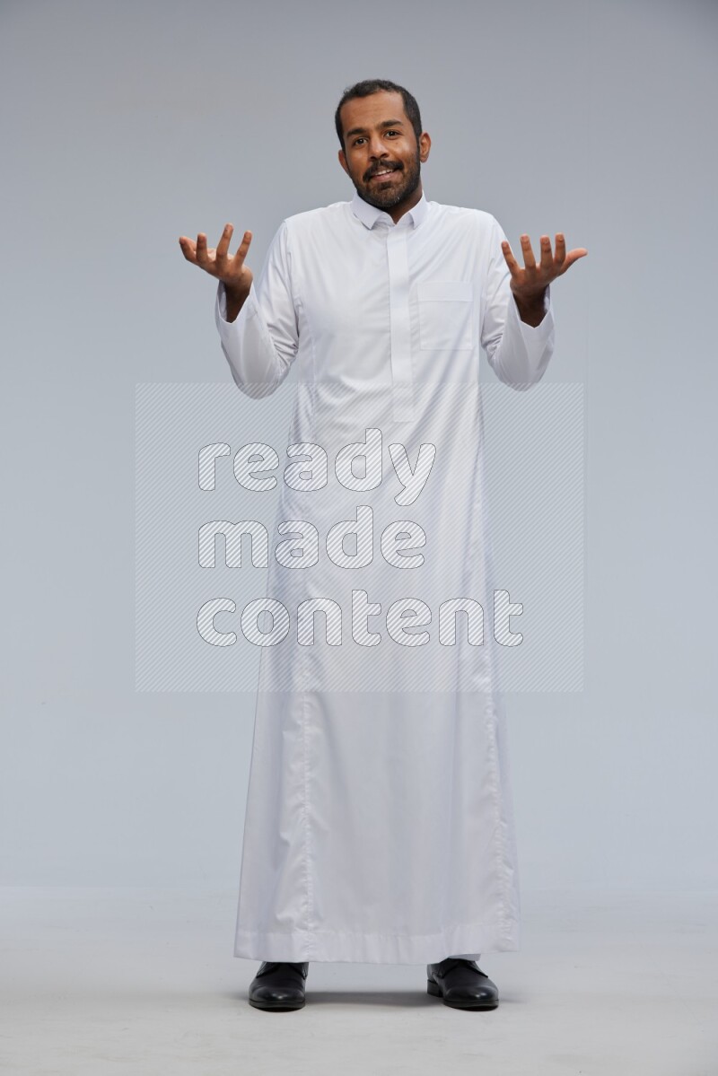 Saudi man Wearing Thob standing interacting with the camera on Gray background