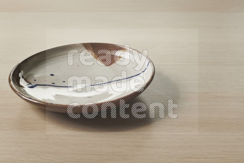 A multicolored pottery plate on light wooden background