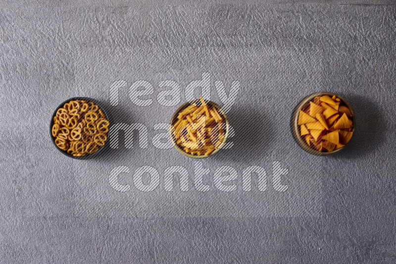 Assorted snacks in pottery bowls on grey background