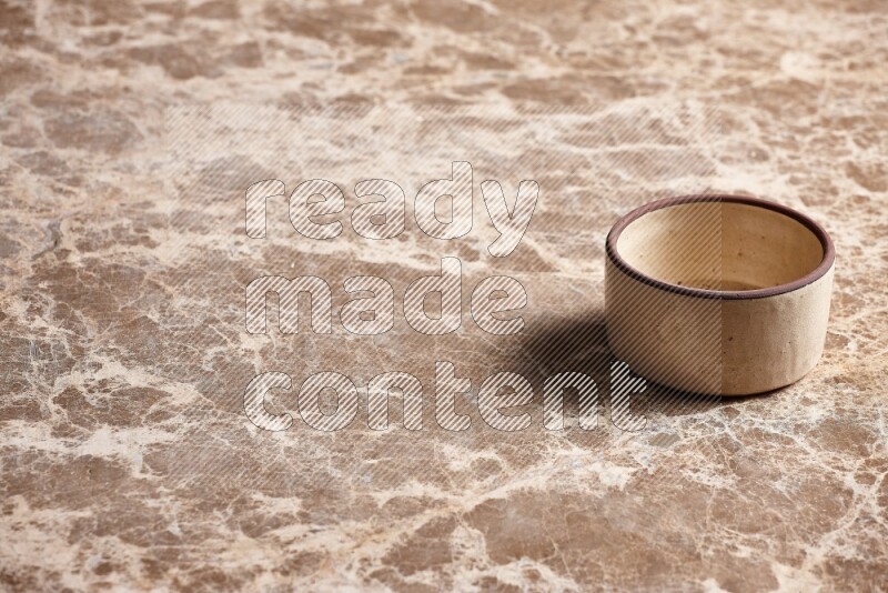 A beige pottery oven bowl on beige marble background