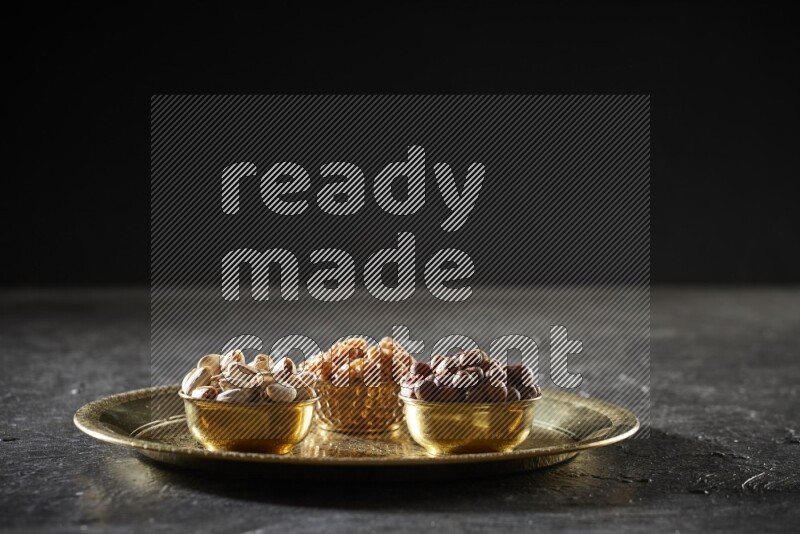 Nuts in metal bowls on a tray in a dark setup