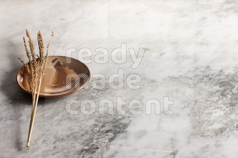 Wheat stalks on multicolored pottery plate on grey marble background