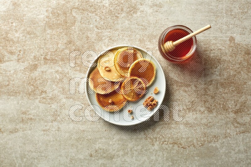 Five stacked dried orange mini pancakes in a blue plate on beige background