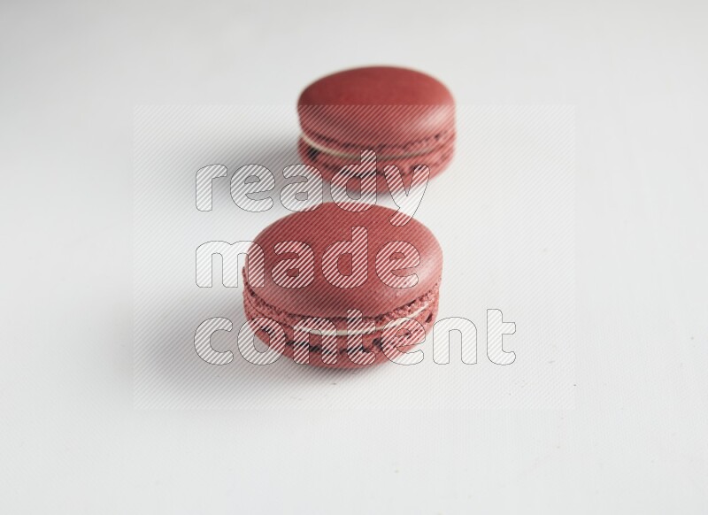 45º Shot of two Red Velvet macarons on white background