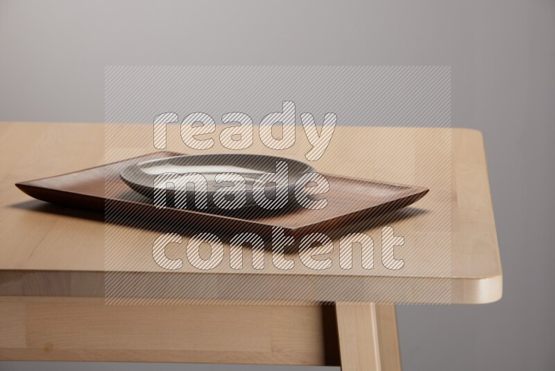 white plate on a rectangular wooden tray on the edge of wooden table