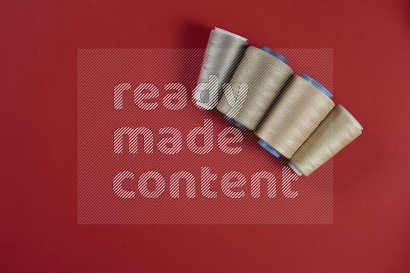 مجموعة من أدوات الخياطة والتفصيل بنية وحمراء اللون على خلفية حمراء