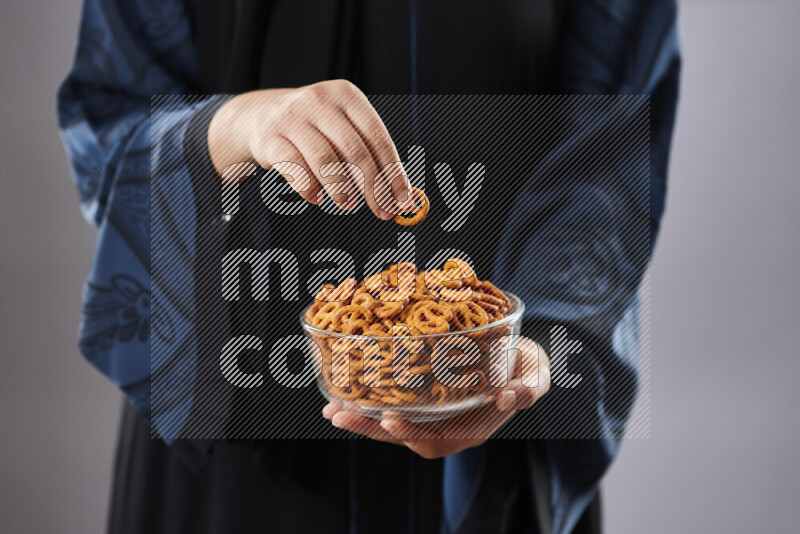 Woman in abaya holding different kinds of snacks in different positions