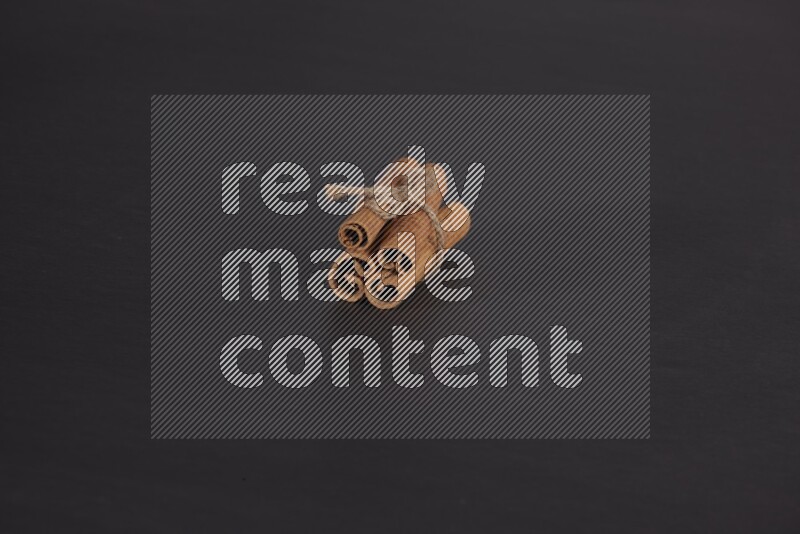 4 أعواد من القرفة مربوطة علي خلفية سوداء