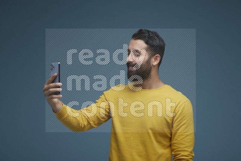 Man Taking a Selfie  in a blue background wearing a yellow shirt