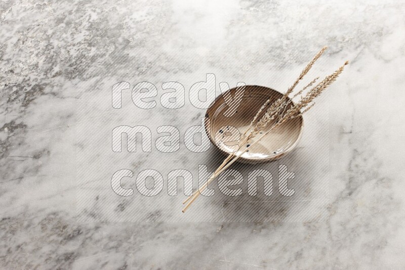 Wheat stalks on multicolored pottery bowl on grey marble background