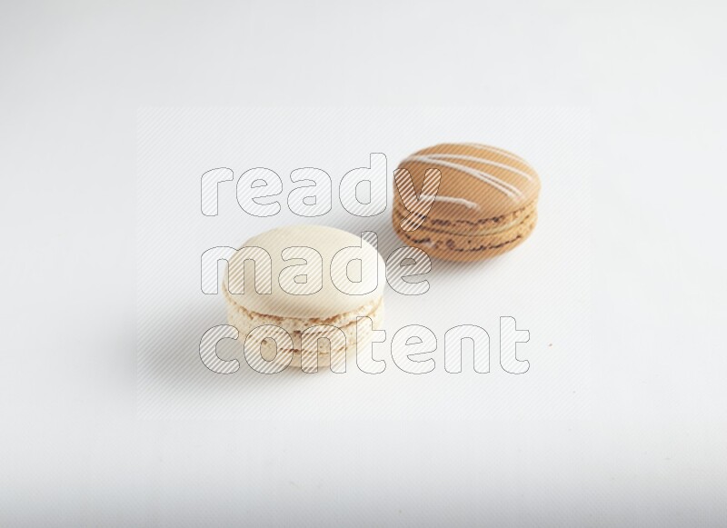 45º Shot of of two assorted Brown Irish Cream, and White Caramel fleur de sel macarons on white background