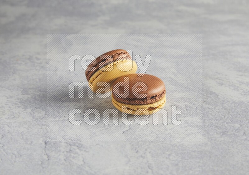 45º Shot of two Yellow and Brown Chai Latte macarons r on white  marble background