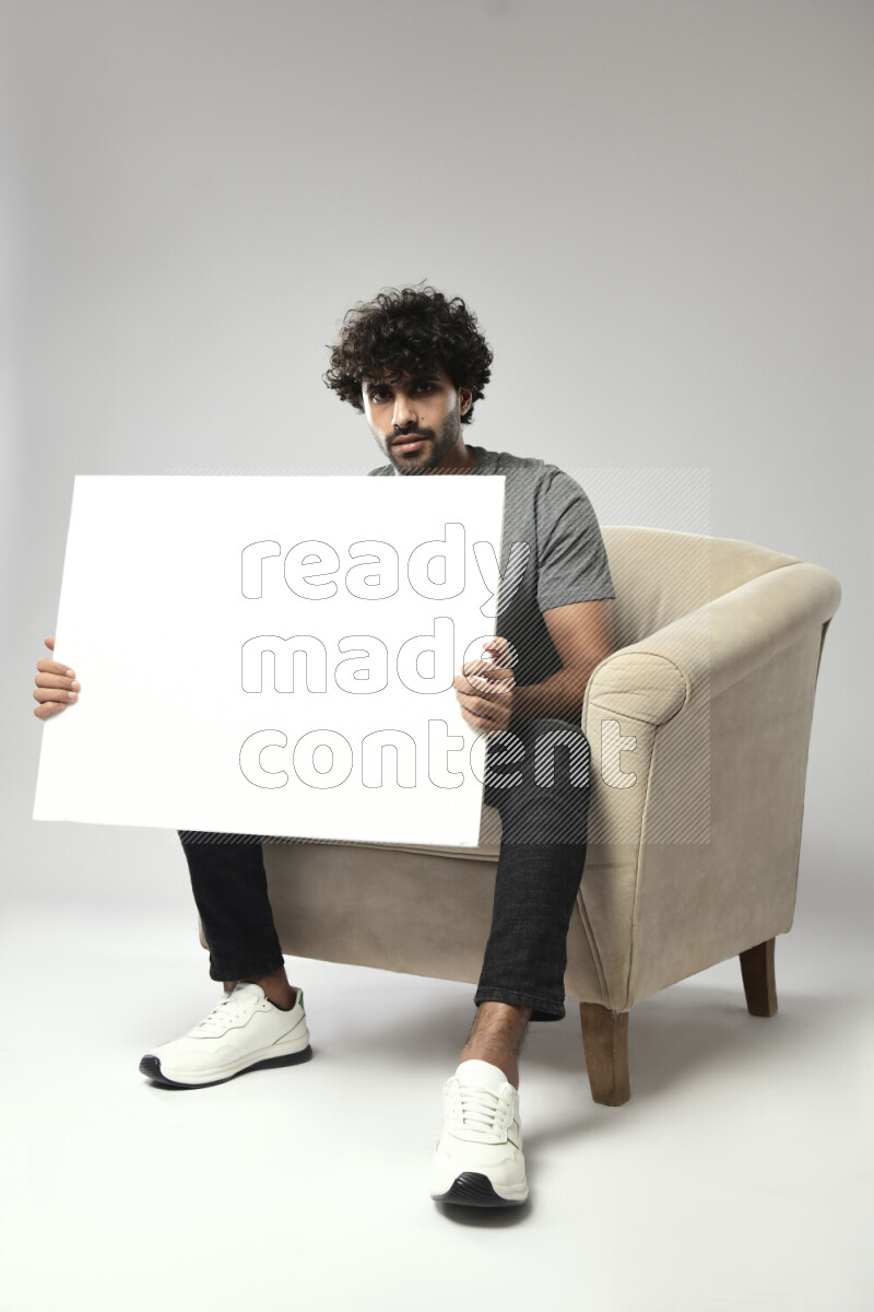 A man wearing casual sitting on a chair holding a white board on white background