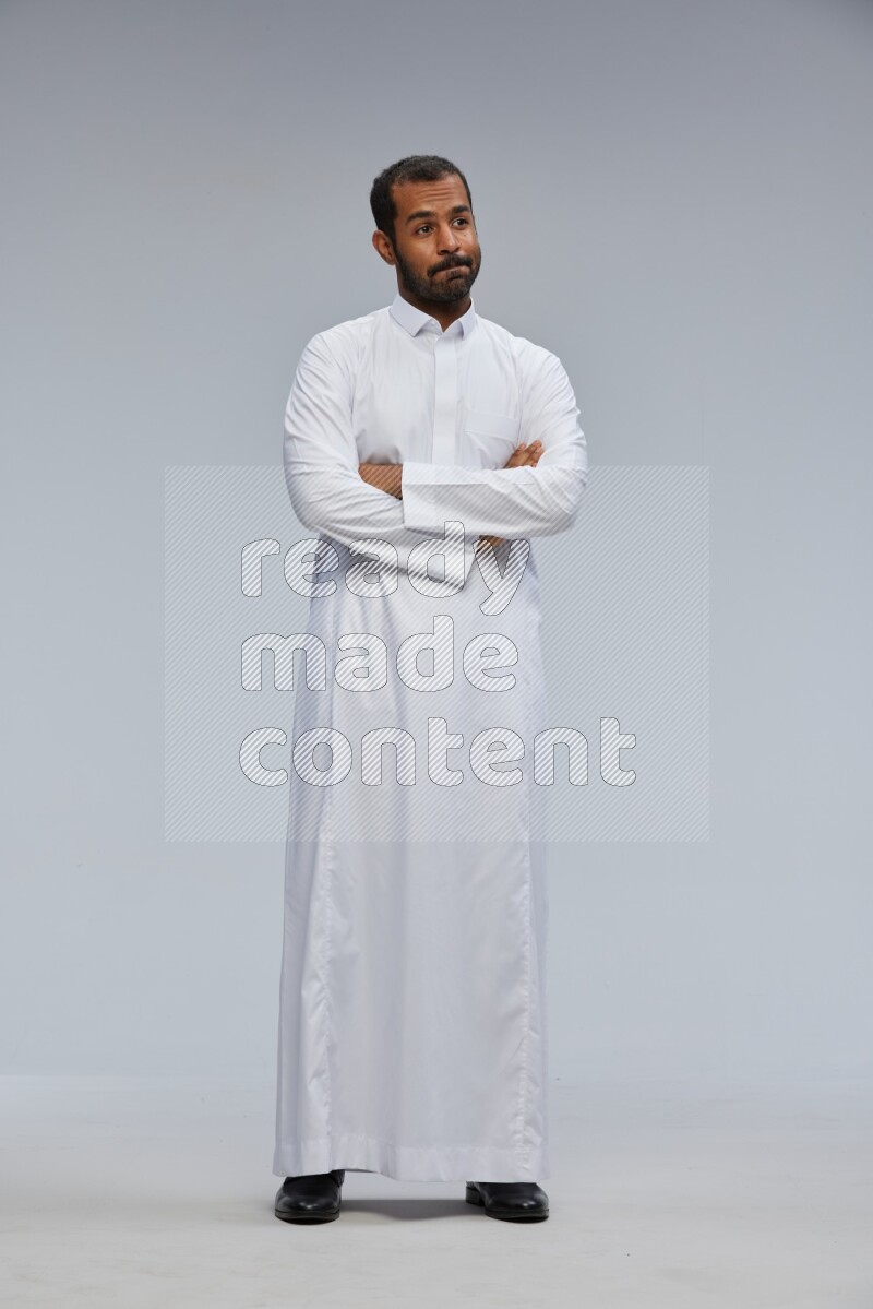 Saudi man wearing Thob standing with crossed arms on Gray background