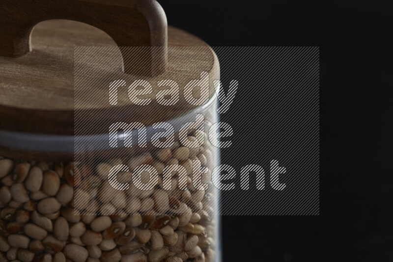 Black-eyed peas in a glass jar on black background