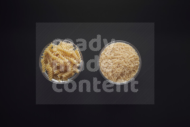 Different pasta types in glass bowls on black background