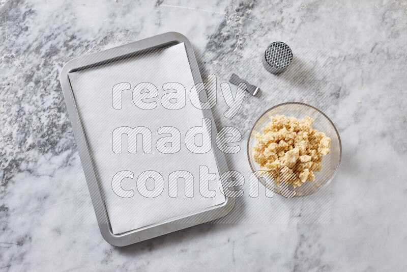 كحك خطوة بخطوة بمكوناته سمن، سكر، دقيق، سمسم، خميرة، ماء ونكهة الكحك على خلفية رخام رمادي