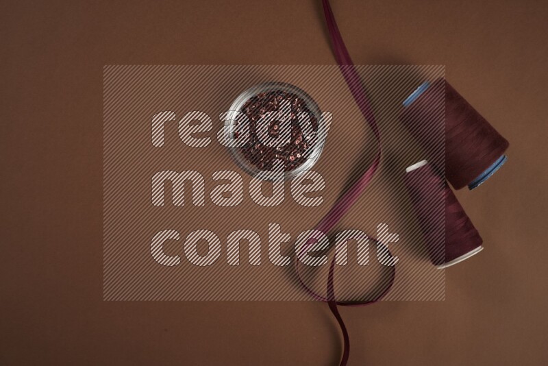 A red collection of sewing and tailoring tools arranged on a brown background
