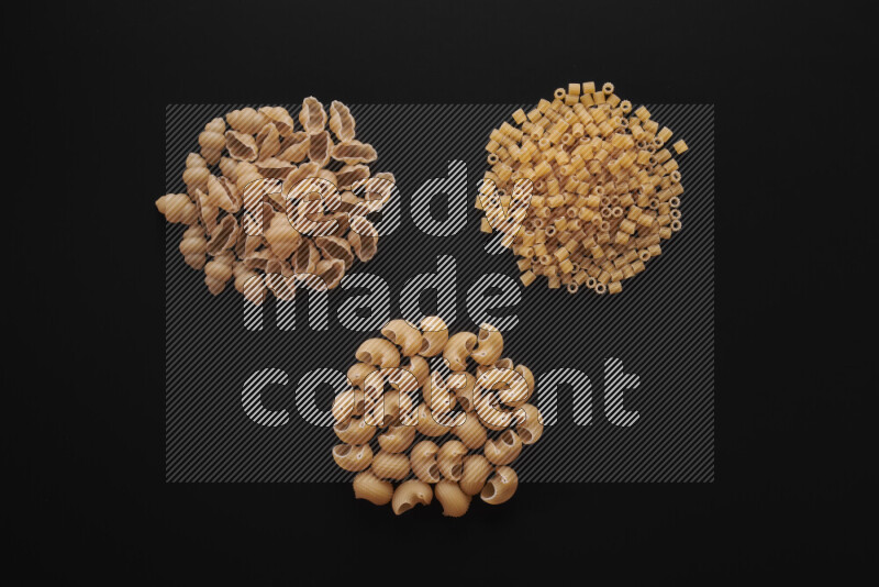 Different pasta types in bunches on black background