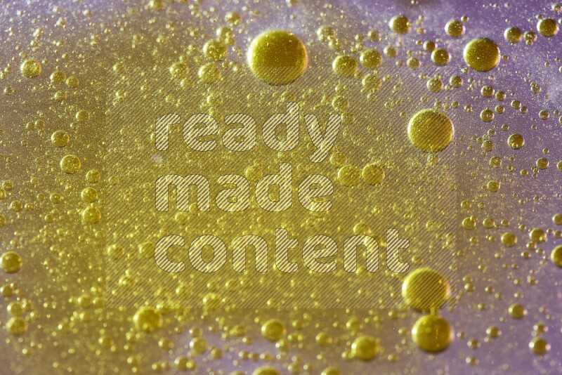 Close-ups of abstract yellow watercolor drops on oil Surface on pink background